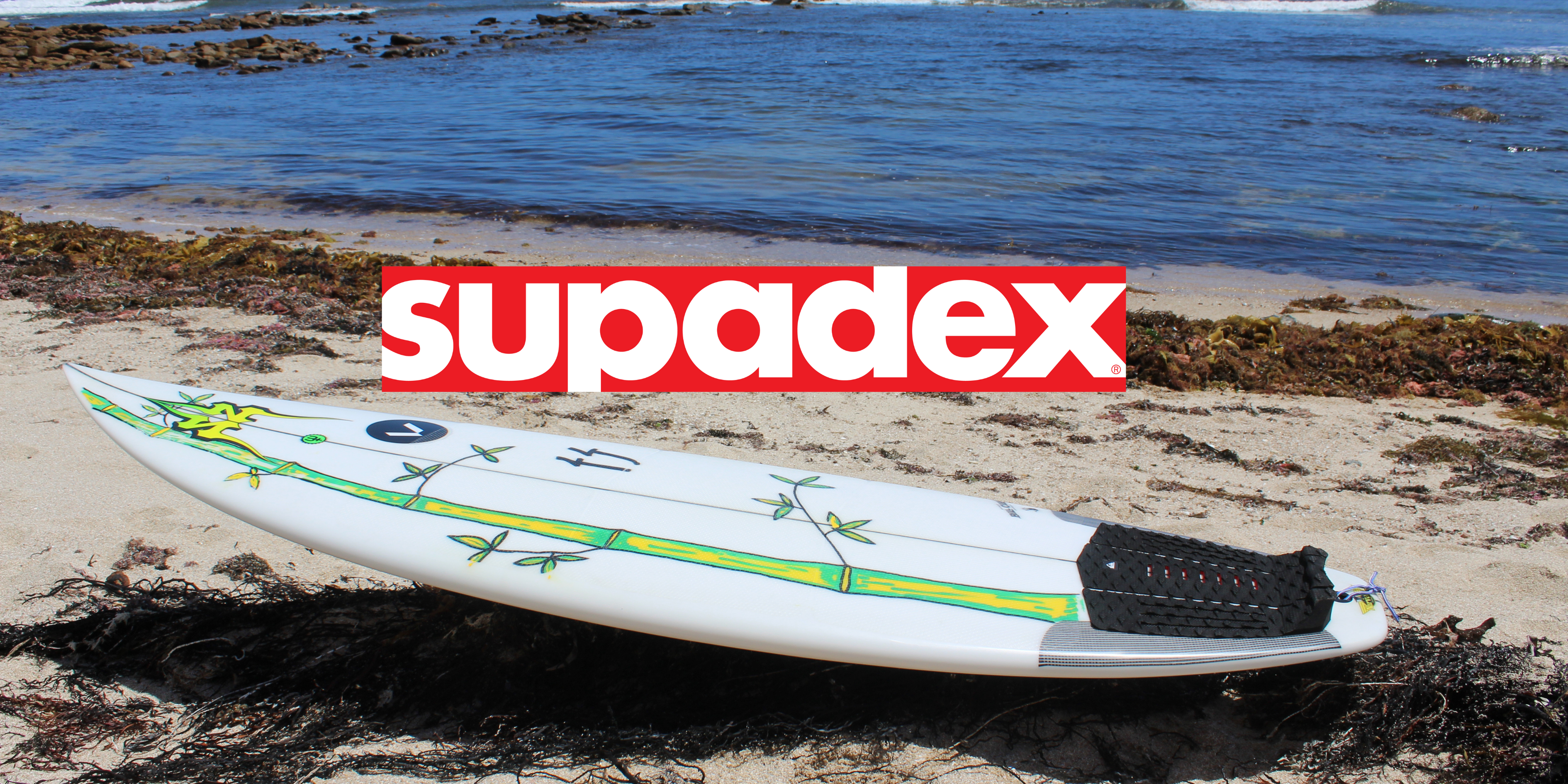 Supadex logo above Supadex surfboard on the beach.